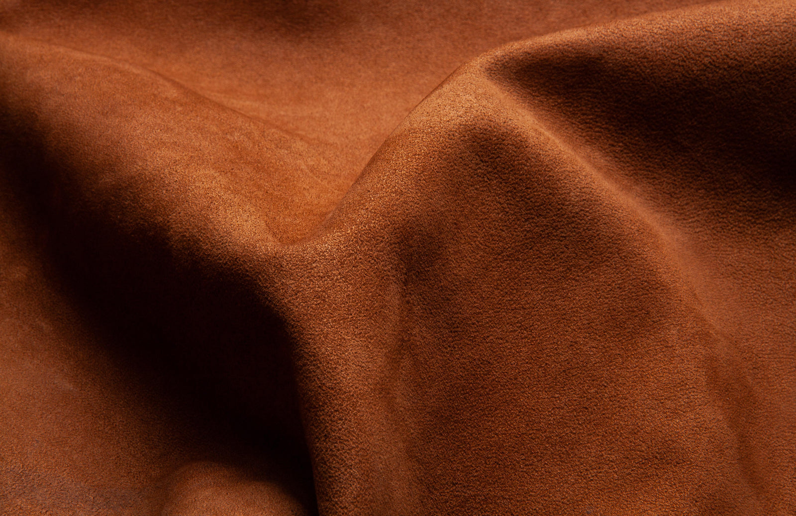 Suede leather. Genuine leather material. Brown background. Beige